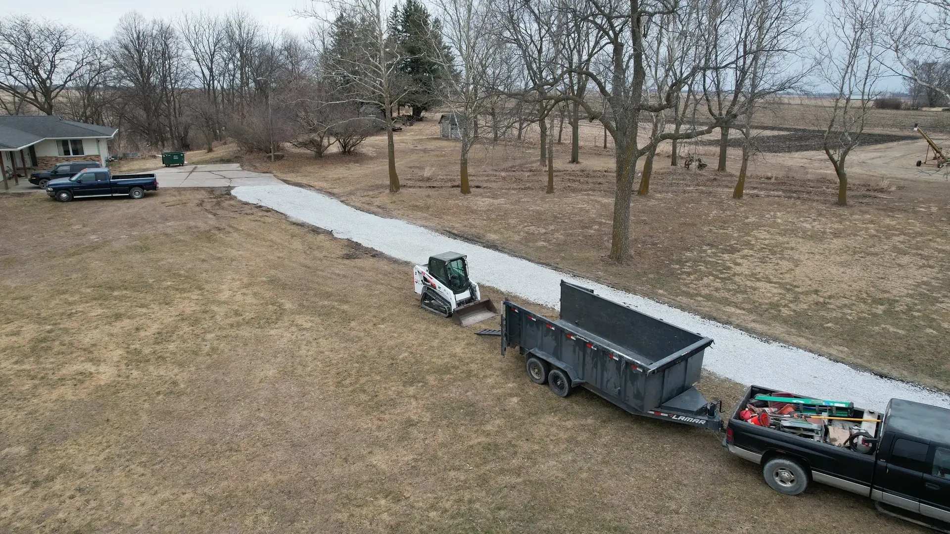Aerial view of a long gravel strip with a dump trailer and truck beside it